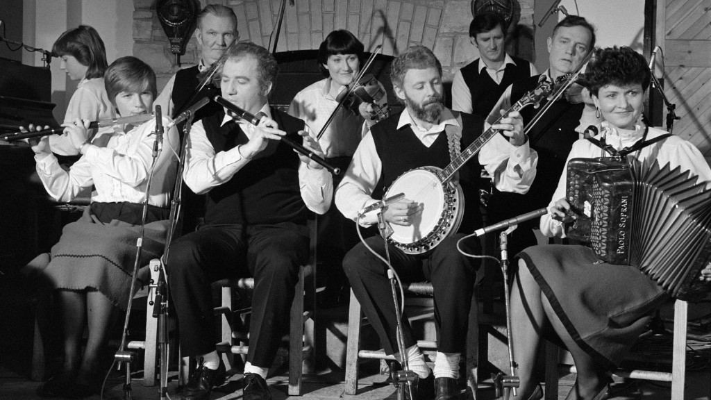 Black-and-white archival photograph of traditional Irish musicians performing with flute, banjo, fiddle, and accordion